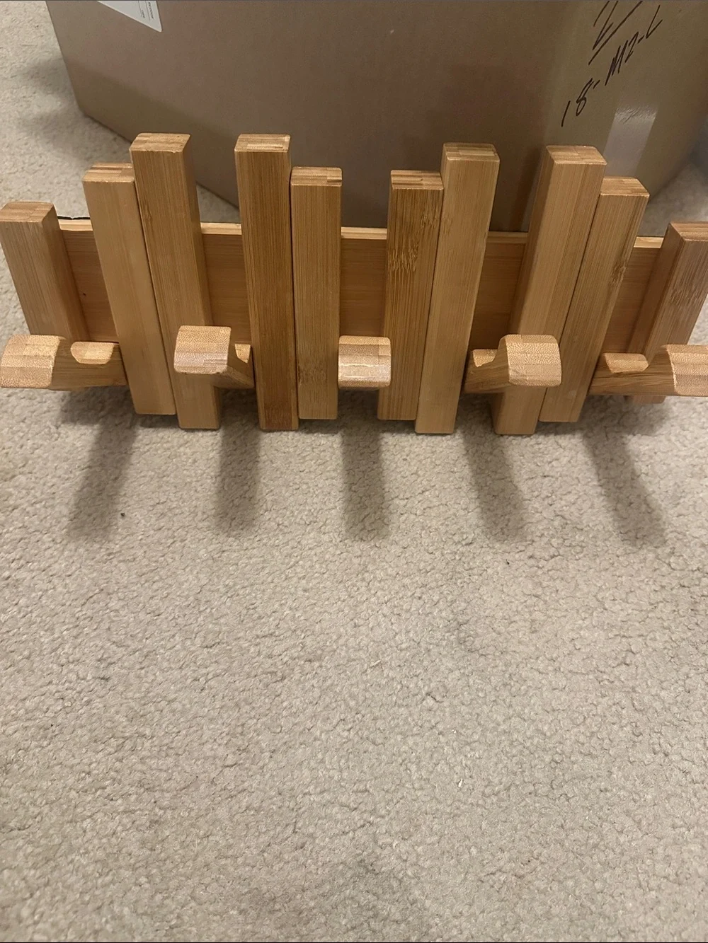 natural wood wall-mounted piano coat rack with flip-down hooks